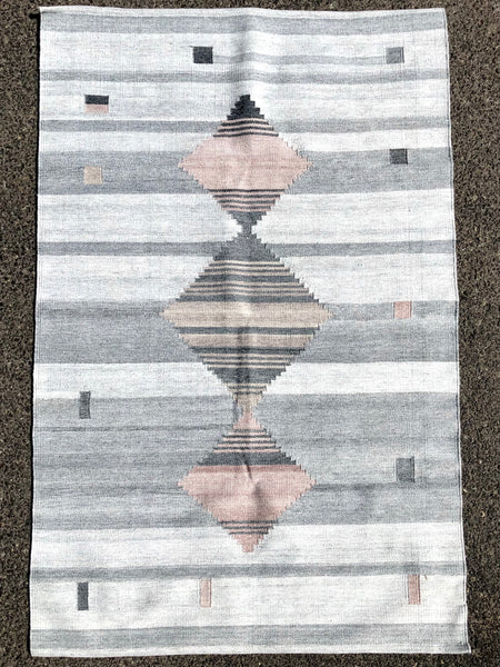 This grey tone background handwoven rug has some shades of grey along with three diamonds, two of them with a touch of mauve.