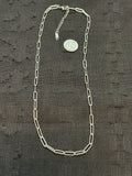 Silver chain with a coin on a textured black fabric background