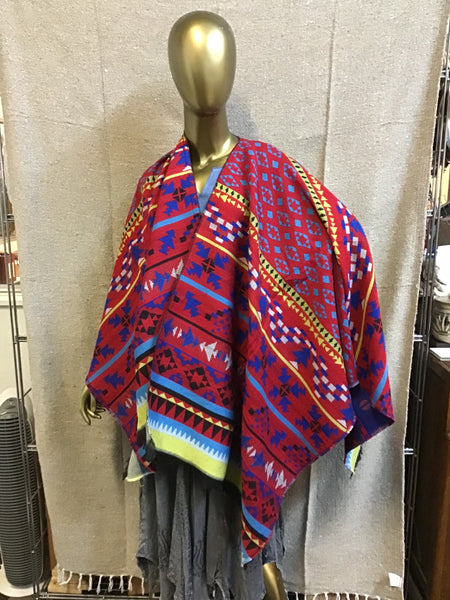 Mannequin wearing a colorful patterned shawl against a neutral background