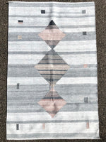 This grey tone background handwoven rug has some shades of grey along with three diamonds, two of them with a touch of mauve.