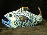 Large fish sculpture with brown rim on fins and tail with blue flowers on side and green leaves.