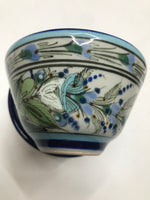Ken Edwards collection series custard bown with blue rim. It is natural grey clay color background with birds, butterflies, and leaves in blue, green, black and brown on the outside.