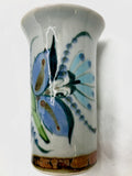 Ken Edwards stoneware vase with brown rim and bottom.  It is natural grey clay color background with birds, butterflies, and leaves in blue, green, black and brown on the outside. 