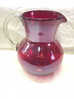 Handblown glass pitcher in solid red with clear glass handle.