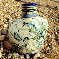 Heart shape vase eith blue rim and green, blue and red ornaments.