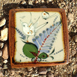 Ken Edwards 6' x 6' stoneware tile.  It is natural grey clay color background with birds, butterflies, and leaves in blue, green, black and brown on the face. 